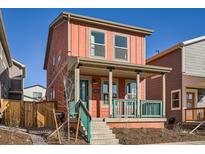 Charming two-story home features a welcoming front porch with teal railing and a vibrant coral exterior at 10331 E 62Nd Pl, Denver, CO 80238