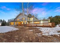 Expansive home exterior with large wooden deck, iron railings, and picturesque mountain views at 1056 County Road 65, Evergreen, CO 80439