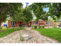 Charming brick home with a stone walkway and landscaped front yard, benches, and a porch swing at 938 Salem St, Aurora, CO 80011