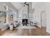 Bright living room with vaulted ceilings, large windows, and fireplace with built-in shelving at 7071 S Gibraltar Way, Centennial, CO 80016