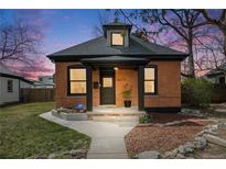 Charming brick home featuring a cozy front porch and manicured lawn at dusk at 4673 Bryant St, Denver, CO 80211