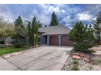 Charming single-Gathering home featuring a two-car garage, lush landscaping, and classic architectural details at 11838 W Arlington Dr, Littleton, CO 80127
