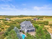 Stunning aerial view of a home with a pool and lush landscaping backing up to an open field at 1635 Sharps Ct, Castle Rock, CO 80109