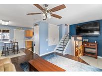 Open-concept living room featuring hardwood floors, a staircase, and seamless flow to the kitchen at 10405 W 107Th Pl, Broomfield, CO 80021