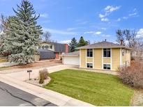Charming yellow two-story home featuring a well-manicured lawn and an attached garage at 1062 Cottonwood St, Broomfield, CO 80020