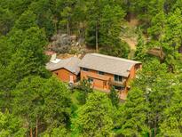 An exterior view of a two story home surrounded by lush trees at 9633 Fox Valley Dr, Morrison, CO 80465