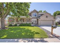 Charming home featuring a covered porch, brick accents, mature trees, and a well-manicured lawn at 1607 Garnet St, Broomfield, CO 80020