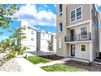 Modern three-story townhome with a stone accent tower, small balcony, and manicured lawn at 11205 W 53Rd Ln, Arvada, CO 80002