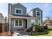 Charming two-story home with light grey siding, a stone chimney, and a well-maintained front yard under a clear blue sky at 11605 E Cornell Cir, Aurora, CO 80014