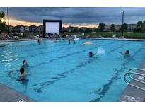 Large community pool with movie screen and many swimmers enjoying a summer day at 6112 Black Mesa Rd, Frederick, CO 80516