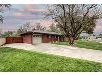 Charming brick home featuring an attached garage and large front yard with mature trees and a long driveway at 6365 S Valleyview St, Littleton, CO 80120