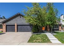Charming home exterior with a three-car garage, concrete driveway, and lush landscaping at 5951 S Akron Way, Greenwood Village, CO 80111