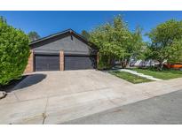 Charming home featuring a two-car garage with stone accents and a spacious driveway for easy parking at 5951 S Akron Way, Greenwood Village, CO 80111