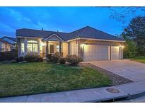 Charming single-story home with a well-manicured lawn and a two-car garage at dusk at 10060 Oak Leaf Way, Highlands Ranch, CO 80129