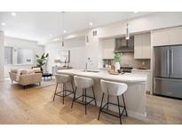 Open-concept kitchen featuring a quartz island with seating, stainless appliances, and bright living area at 1256 Xavier St, Denver, CO 80204