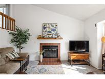 Cozy living room featuring a brick fireplace, mantel, and comfortable seating area at 7659 Depew St, Arvada, CO 80003
