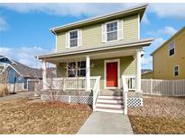 Two-story house with a green exterior, front porch, and red door at 9437 E 108Th Dr, Commerce City, CO 80640