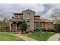 Charming stone home with a well-manicured lawn and inviting front porch with a wood-supported roof at 9592 Firenze Way, Highlands Ranch, CO 80126