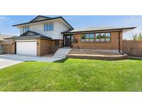 Inviting two-story home featuring a brick facade, well-manicured lawn, and attached two-car garage at 13390 W Warren Ave, Lakewood, CO 80228