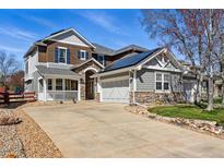 Two-story home with a front porch, attached garage, stone accents, and solar panels on the roof at 6273 Torrey Ln, Arvada, CO 80403