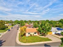 Cozy tan home with a manicured lawn, a street corner view, and mature trees surrounding the property at 701 Tucson, Aurora, CO 80011