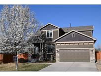 Charming two-story home with a well-manicured lawn, blooming tree, and a two-car garage at 9121 Harlequin Cir, Frederick, CO 80504