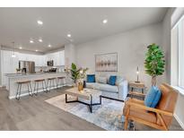 Open-concept living room with a modern kitchen, breakfast bar, and comfortable seating area at 5179 S Fairplay St, Aurora, CO 80015