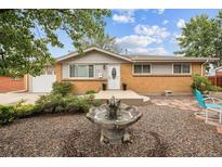 Charming ranch-style home boasts a well-maintained front yard with a decorative water feature and manicured landscaping at 8460 Corona St, Denver, CO 80229