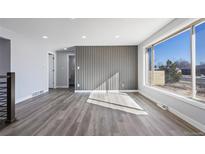 Bright living room features updated gray wood flooring, a large window and a designer gray accent wall at 951 E 10Th Ave, Broomfield, CO 80020