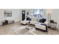 Bright living room features a large window and a comfortable white sectional sofa with throw pillows at 1005 Elmer Dr, Northglenn, CO 80233