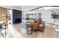 Bright living room featuring a black brick fireplace, hardwood floors, and many windows at 2435 S Meade St, Denver, CO 80219
