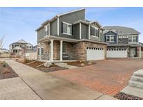 Charming two-story home with a stone facade, covered porch, and two-car garage, showcasing curb appeal and modern design at 4138 N Quatar Ct, Aurora, CO 80019
