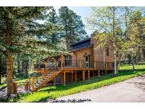 Charming brick home with a spacious deck surrounded by lush greenery at 25357 Snyder Ave, Conifer, CO 80433