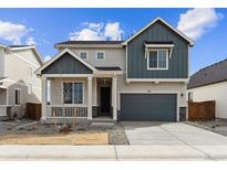 Two-story home featuring a charming front porch, gray siding, well-manicured landscaping, and an attached two-car garage at 190 Lark Sparrow Way, Bennett, CO 80102
