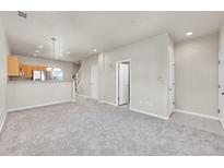 Bright living room with neutral carpet, white walls, and a view into the kitchen with stainless steel appliances at 1401 W 85Th Ave # F201, Federal Heights, CO 80260