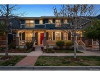 Charming two-story home featuring a welcoming front porch with beautiful landscaping and a striking red front door at 9446 E 51St Dr, Denver, CO 80238
