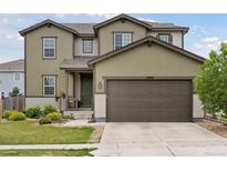 Two-story home with green siding, a dark brown garage door, and well-maintained landscaping at 4280 Pioneer Pl, Brighton, CO 80601