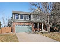 Charming two-story home featuring a brick facade, green siding, and a well-manicured front yard at 5134 S Fraser Way, Aurora, CO 80015