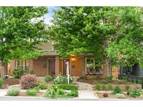 Charming brick home with lush landscaping, mature trees, and inviting front porch at 4511 Perry St, Denver, CO 80212