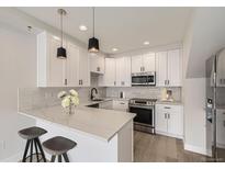 Bright kitchen with white cabinets, marble countertops, stainless steel appliances, and modern pendant lighting at 1462 Yates St, Denver, CO 80204