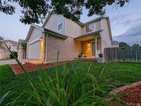 Two story home with tan siding, brick accents, and a well-maintained lawn and landscaping at 3982 S Himalaya Way, Aurora, CO 80013