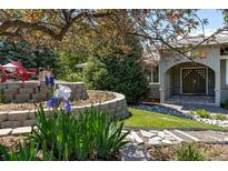 Inviting front entrance with stone walkway, manicured landscaping, mature trees, and a charming red Adirondack chair at 5631 Silver Bluff Ct, Parker, CO 80134