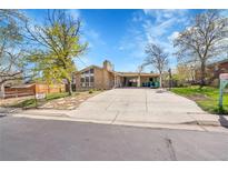 Charming brick home featuring a spacious driveway, and well-maintained landscaping with beautiful trees and greenery at 414 S Nelson S St, Lakewood, CO 80226