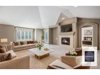 Spacious living room features a cozy fireplace, large windows, and elegant neutral furnishings at 13806 E Chenango Dr, Aurora, CO 80015