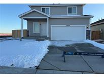 Charming two-story home with a large white garage door and inviting front porch at 48290 Shetland Dr, Bennett, CO 80102