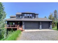 Attractive three-car garage home with ample windows and outdoor deck with mountain views at 30889 Manitoba Dr, Evergreen, CO 80439