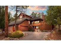Stunning wood home with a deck, mature trees, stone accents, and a long driveway at 29857 Park Village Dr, Evergreen, CO 80439