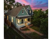Charming home featuring a covered front porch, brick garden beds, and walkway, framed by mature trees at dusk at 2527 W Dunkeld Pl, Denver, CO 80211