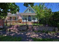 Charming blue home featuring a well-manicured front yard and black iron fence at 2527 W Dunkeld Pl, Denver, CO 80211