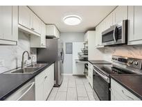 A modern kitchen with white cabinetry, stainless steel appliances, and sleek black countertops at 4940 E Donald Ave # 8, Denver, CO 80222